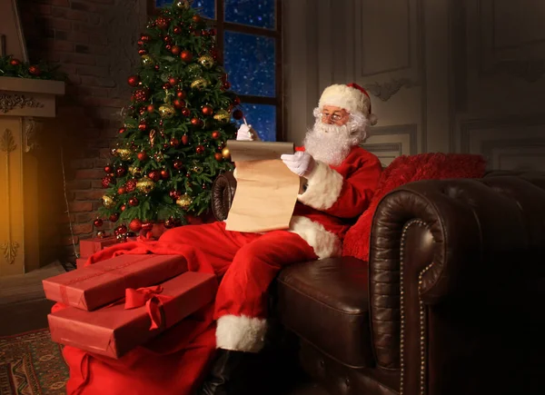 幸せなサンタクロースの肖像クリスマスツリーの近くの自宅で彼の部屋に座って クリスマスの手紙や願いのリストを読む — ストック写真
