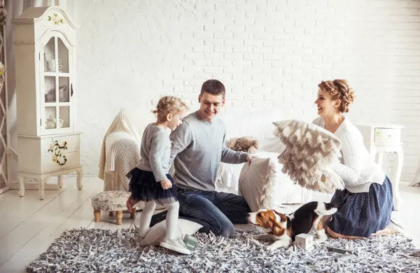 happy family and pet dog playing with pillows in spacious living room