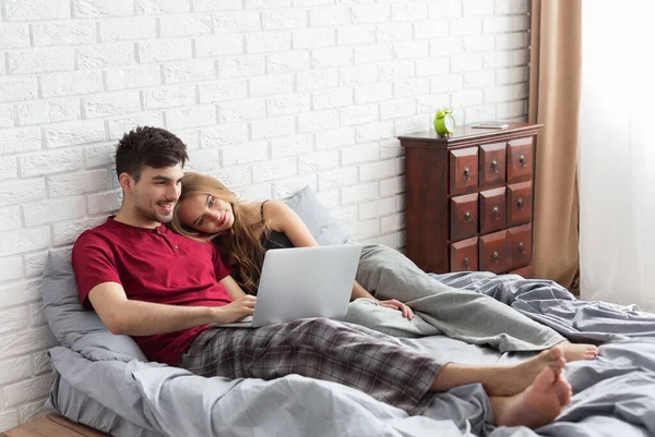 年轻夫妇躺在床上 用笔记本电脑 — 图库照片