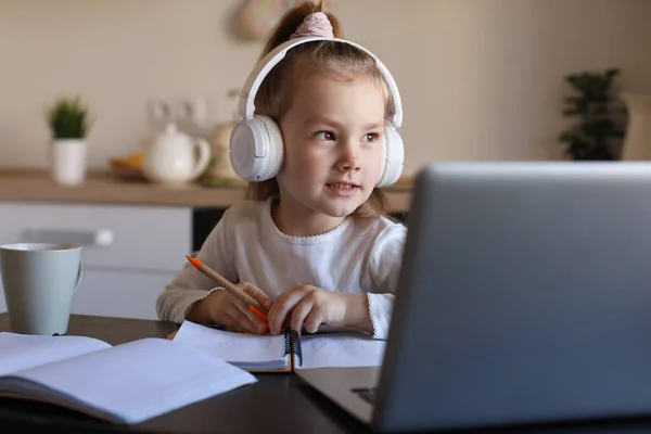 Kulaklıkla Gülümseyen Küçük Bir Kız Evde Dizüstü Bilgisayar Kullanıyor Kulaklıklı — Stok fotoğraf