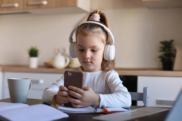 Kulaklıklı Akıllı Küçük Kız Akıllı Telefon Üzerine Ödev Yapıyor Kulaklık — Stok fotoğraf