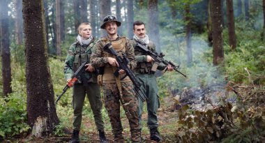 Askeri üniformalı bir grup asker ormanda tüfek taşıyor. 