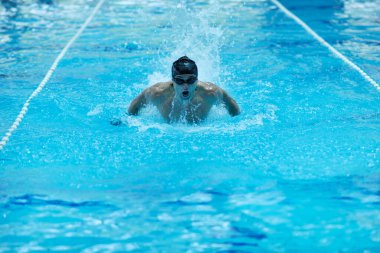 Erkek sporcu yüzme havuzunda yüzüyor 