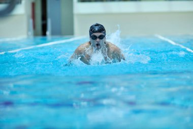 Erkek sporcu yüzme havuzunda yüzüyor 