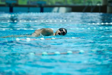 Erkek sporcu yüzme havuzunda yüzüyor 