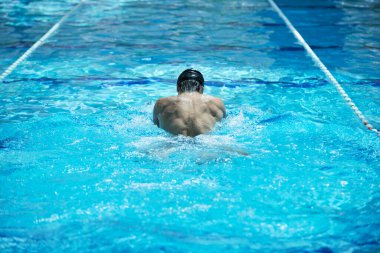 Erkek sporcu yüzme havuzunda yüzüyor 