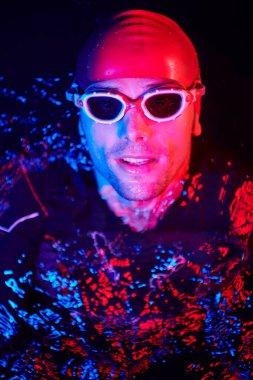 Otantik triatlet yüzücüsü gece güneşli jel üzerinde çalışırken mola veriyor.