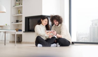 çok ırklı çift şömine önünde tablet bilgisayar kullanarak