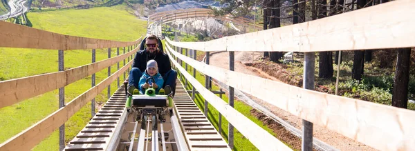 stock image young father and son driving alpine coaster