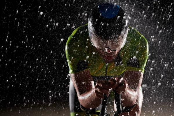 雨の夜に速く自転車に乗るトライアスロン選手 — ストック写真