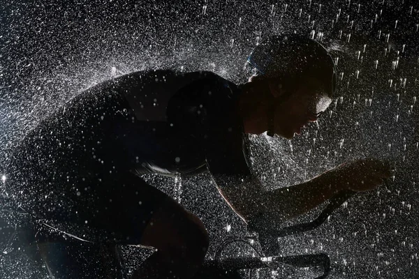 雨の夜に速く自転車に乗るトライアスロン選手 — ストック写真