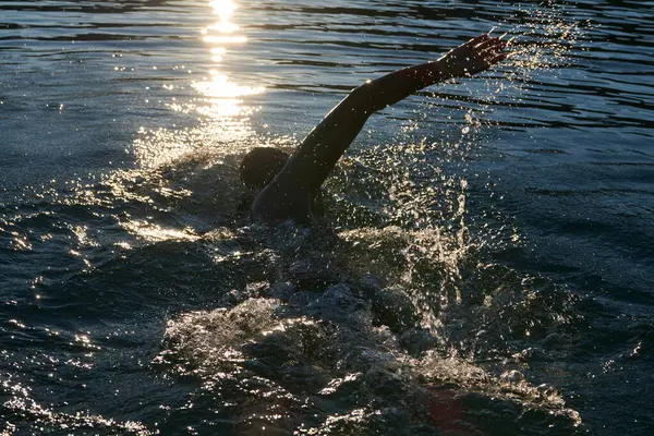 トライアスロン選手がウェットスーツを着て日の出に湖を泳ぎ — ストック写真