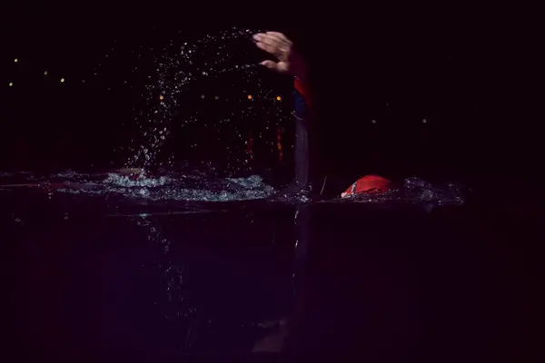 三项全能运动员穿着湿衣在漆黑的夜晚游泳 — 图库照片