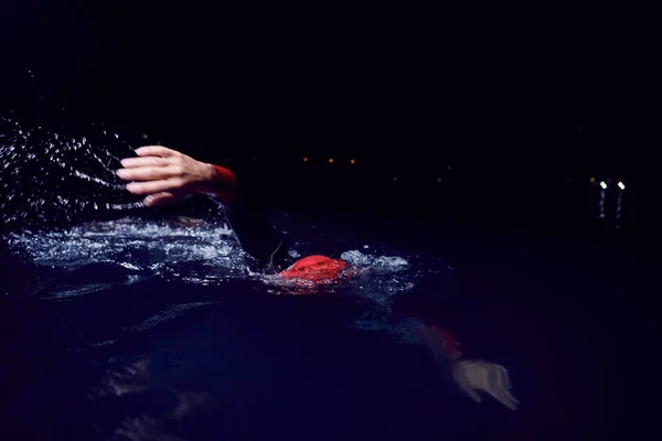 三项全能运动员穿着湿衣在漆黑的夜晚游泳 — 图库照片