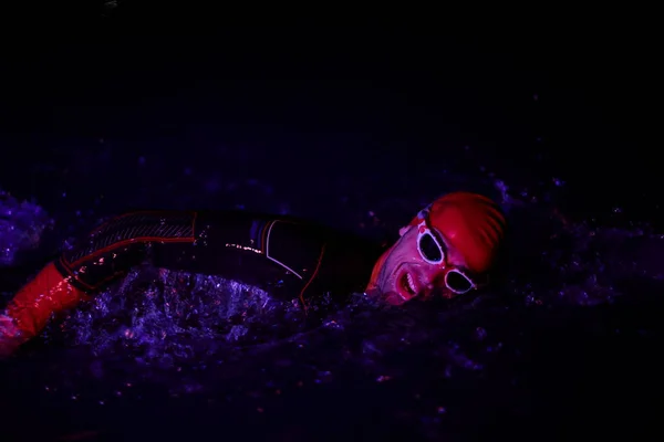 真のトライアスロン選手は暗い夜に泳ぎ — ストック写真