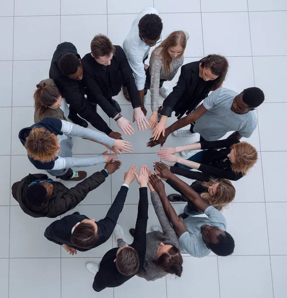 group of young successful people stands around hands together