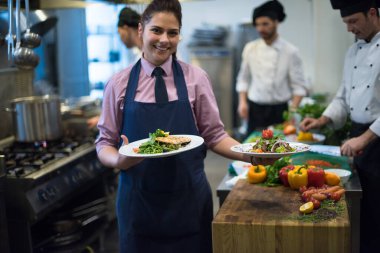 Genç garson lezzetli yemekler gösteriyor.