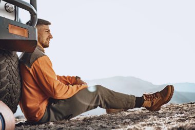 Yürüyüş yapan genç bir erkek mola yerinde dinleniyor.