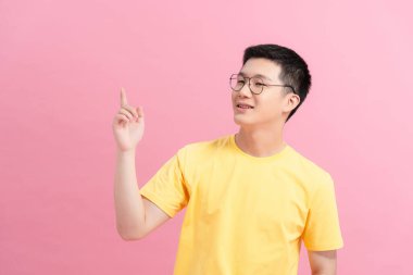 smiling young handsome Asian man pointing fingers in empty space aside