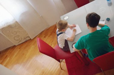 Anne küçük oğluna ödevlerinde yardım ediyor.