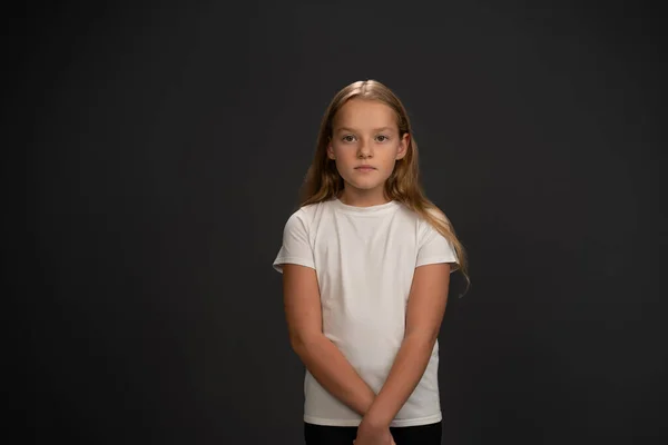 Mała Dziewczynka Stojąca Wypytująca Lub Sfrustrowana Kamerą Białej Koszulce Ciemnoszarym — Zdjęcie stockowe