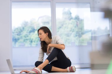 yere dizüstü bilgisayar kullanan genç kadın