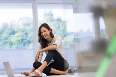 yere dizüstü bilgisayar kullanan genç kadın