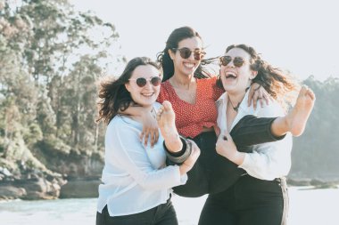 Happy young women laughing and smiling at the beach on a summer day, enjoying vacation, concept of friendship enjoying the outdoor
