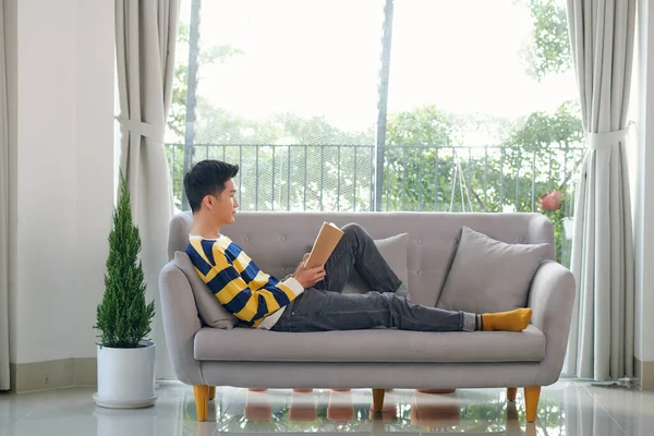 Young Man Reading Book While Sitting Couch — 图库照片