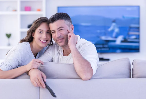 Young couple on the sofa watching television top view