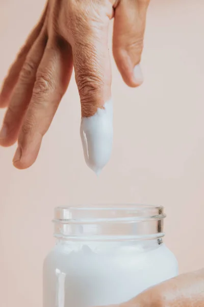 Elderly Woman Rubbing Hand Cream Close Minimal Pastel Background Copy — ストック写真