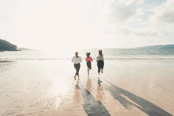 幸せな女性の友人は明るい日の間に海のビーチで走り 友人は夕方の日没時に海の近くのビーチで楽しんでリラックスしてください — ストック写真