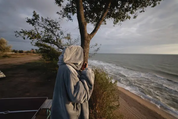 若い女性はスマートフォンで海の夕日の写真を撮る — ストック写真