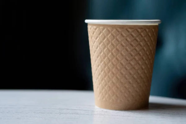 Take away a plastic cup of coffee on a wooden table with a blurred background with space for text or advertising.