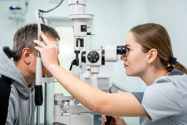 Ophthalmologist and patient testing eyesight. Man doing eye test with optometrist. Ophthalmologist using apparatus for eye examination in clinic. Doctor examining patient doing eyesight measurement