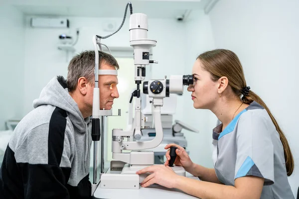 Doctor and patient in ophthalmology clinic. Male patient checking vision with special eye equipment. Optometry concept. Man visiting optician. Patient at slit lamp of optician or optometrist