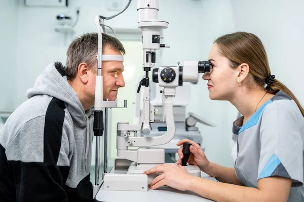 Optometrist examining the eyes of a male patient in a modern ophthalmology clinic. Eye doctor with man patient during an examination in modern clinic. Optometry concept. Eyesight exam in clinic