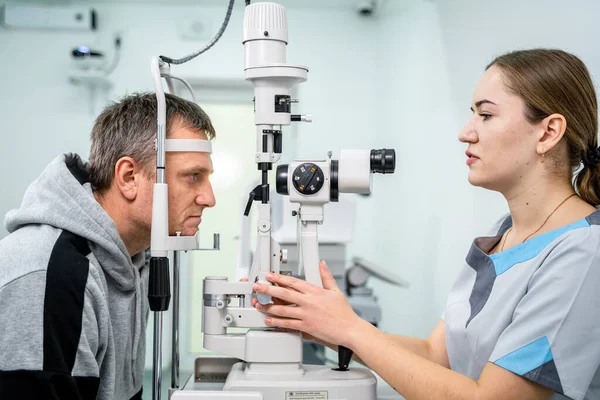 Doctor and patient in ophthalmology clinic. Male patient checking vision with special eye equipment. Optometry concept. Man visiting optician. Patient at slit lamp of optician or optometrist
