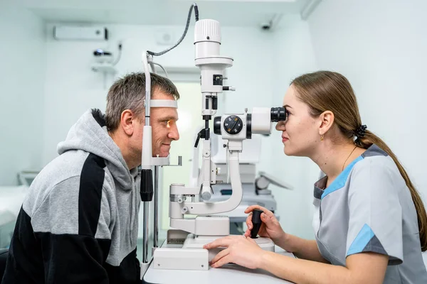 Ophthalmologist and patient testing eyesight. Man doing eye test with optometrist. Ophthalmologist using apparatus for eye examination in clinic. Doctor examining patient doing eyesight measurement