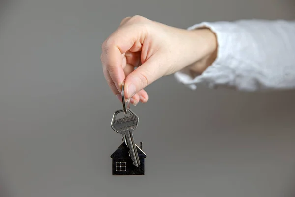 Real estate agent with house model and keys, selling house, property owner mortgage concept with copy space on gray background