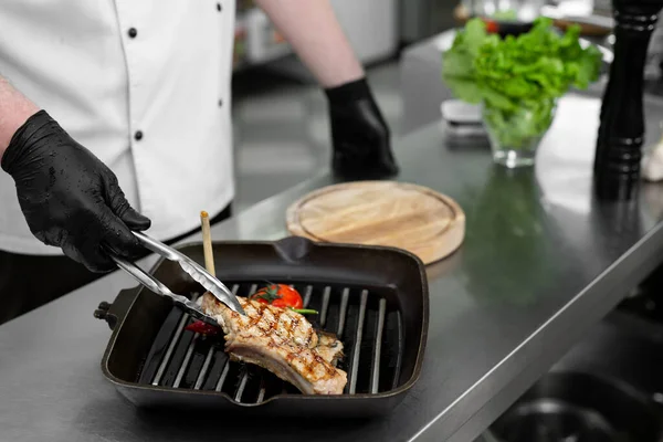 グリルステーキと野菜のグリルパンを持つシェフの手のクローズアップ — ストック写真