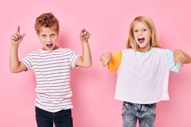 Çocukluk dönemindeki pembe arka planda el kol hareketleri yapan komik çocuklar.