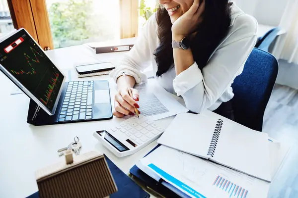 财务报表和投资一位笑容满面的亚洲女人拿着一支钢笔 为她的公司使用股票市场回报率计算器 — 图库照片