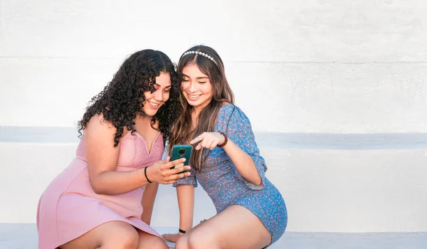 两个女孩指着她的手机 女孩把她的智能手机给她的朋友看 女孩和她的朋友一起检查她的手机 — 图库照片