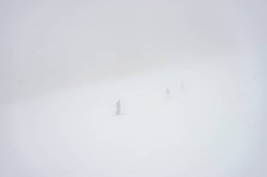 Sisli bir günde yamaçlarda kayakçılar