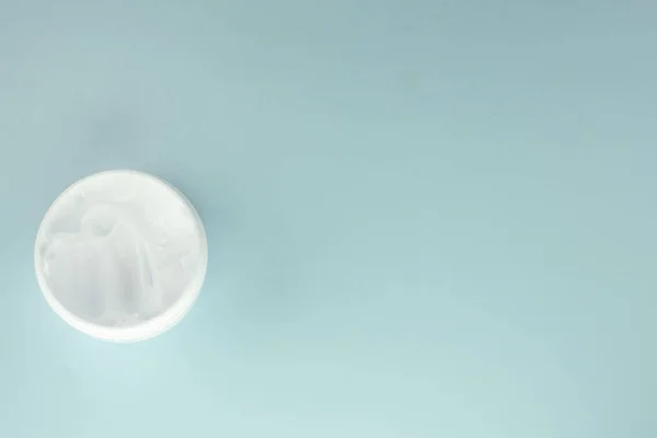 白色化妆品面霜在一个圆形的开放的罐子里 浅蓝色背景 顶视图 右边的空间复制 — 图库照片