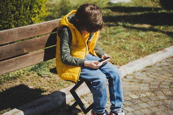 Schoolboy Joue Jeu Son Téléphone Portable Assis Sur Banc Dans — Photo