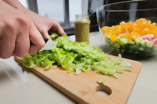 女の子の手のクローズアップは 木製のテーブルの上にサラダをカット 女性はベジタリアンサラダを準備 健康食品 ナイフカット緑 — ストック写真