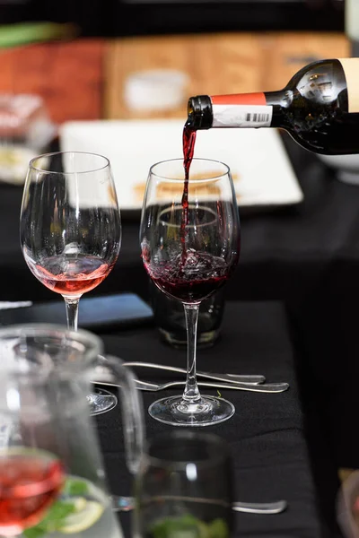 Versare Vino Rosso Nel Bicchiere Sullo Sfondo Della Tavola Servita — Foto Stock