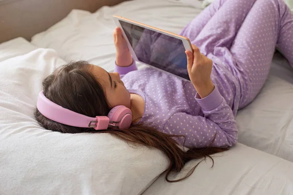 Pieni Tyttö Violetissa Pyjamassa Makaa Valkoisella Sängyllä Selällään Pitää Vaaleanpunaista — kuvapankkivalokuva